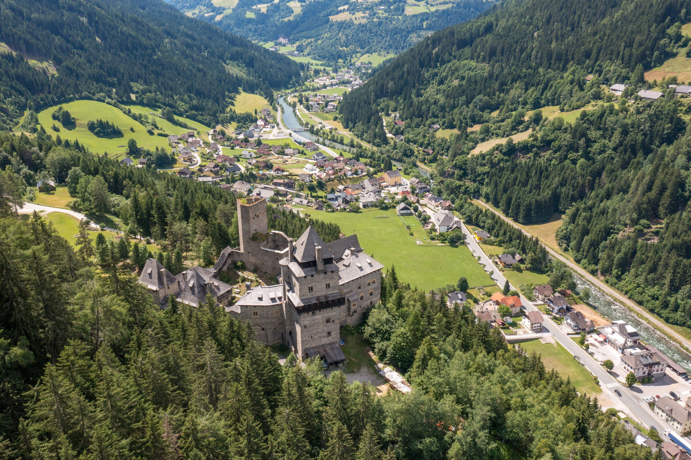 Historische Burg über grünen Tälern, umgeben von majestätischen Wäldern und charmanten Dörfern.