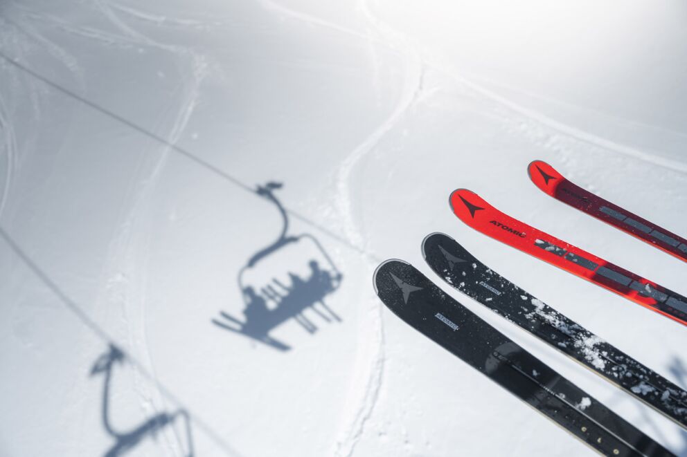 Skier im Schnee unter einem Sessellift auf einer Skipiste.