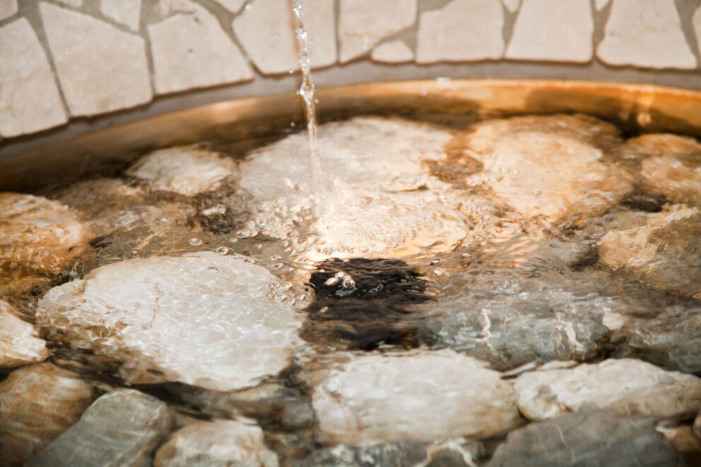 Sprudelndes Wasser in einem steinernen Becken mit natürlichen Details.