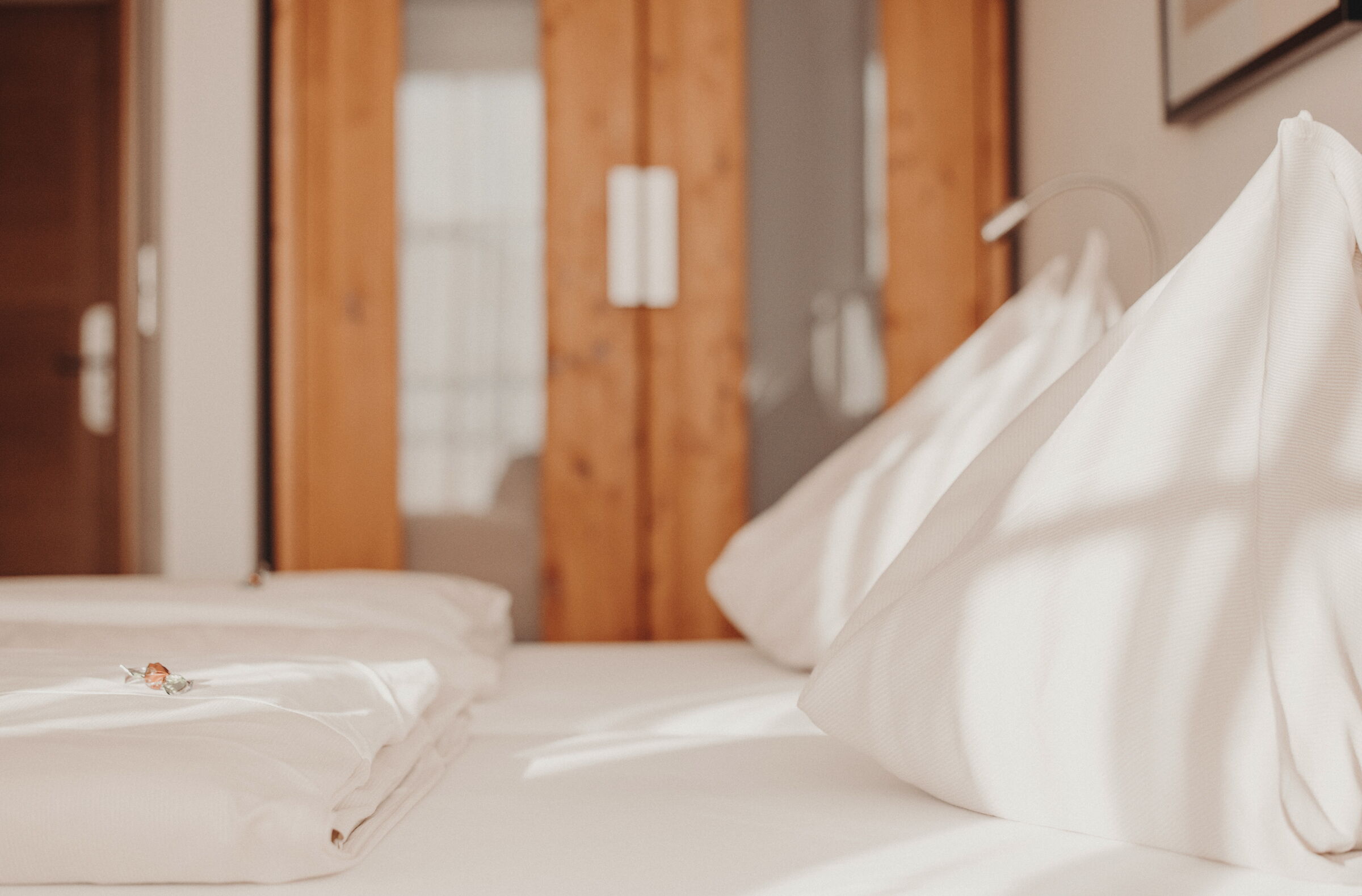 Bright, inviting hotel room with white cushions and wooden furniture in the sunlight.