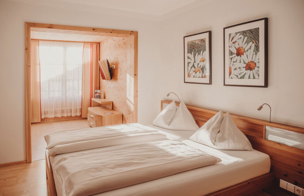 Helles Schlafzimmer mit Holzelementen, großen Fenstern und stilvollen Dekorationen.