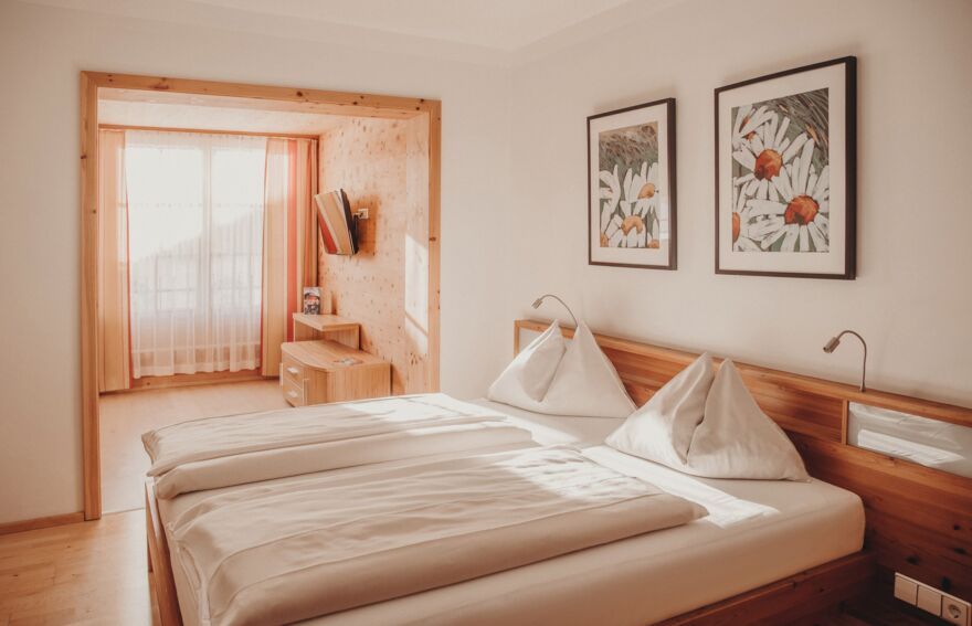 Sonniges Zirbenzimmer im Hotel Binggl in Mauterndorf/Lungau mit Doppelbett und gemütlichem Anbau