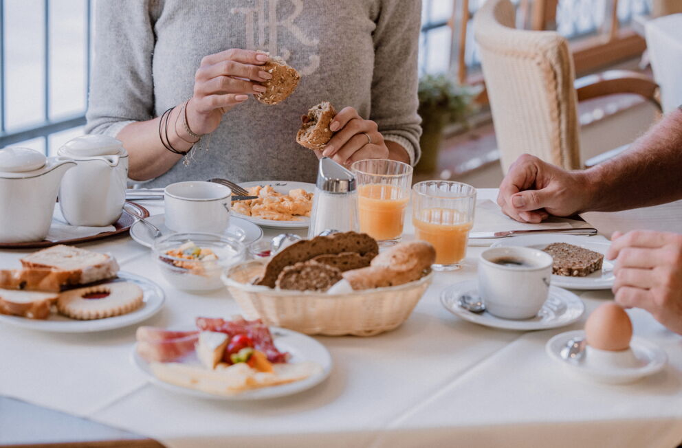 Menschen genießen Frühstück mit Brot, Kaffee, Orangensaft und Gebäck.