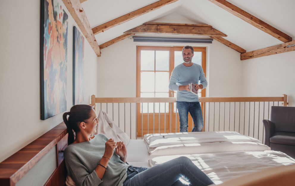 Mann und Frau genießen entspanntes Ambiente in lichtdurchflutetem Dachzimmer mit Holzdetails.