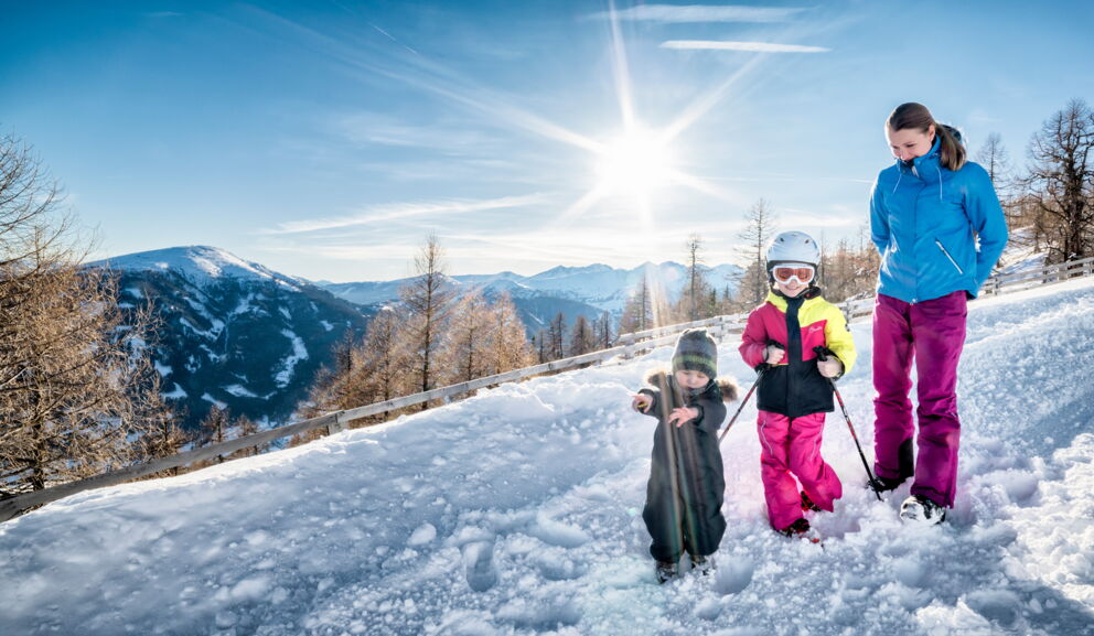 Familie genießt sonnigen Wintertag in den verschneiten Bergen bei strahlend blauem Himmel.