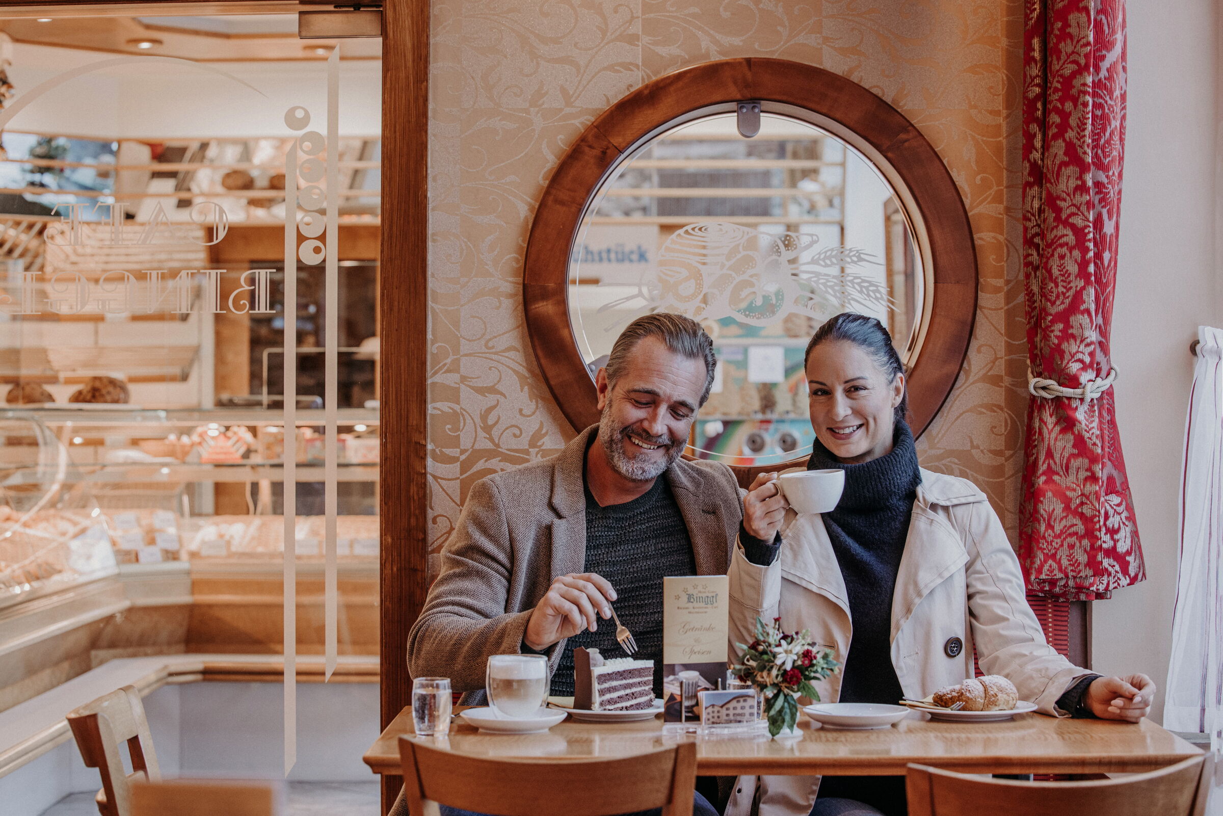 Zwei Personen genießen Kaffee und Kuchen in einem gemütlichen Café mit Spiegel.