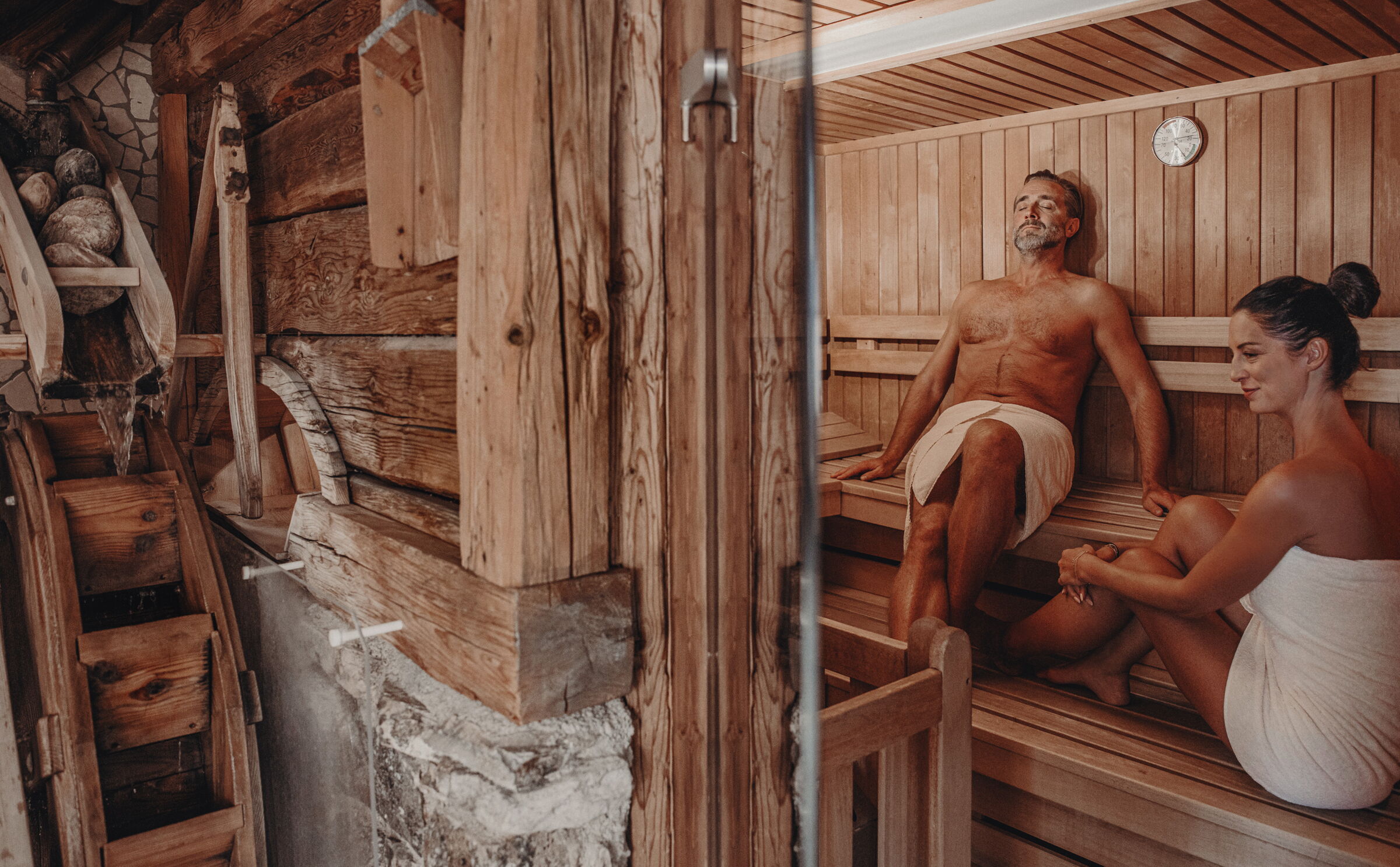 Zwei Personen entspannen in einer Sauna aus natürlichem Holz mit gemütlicher Atmosphäre.