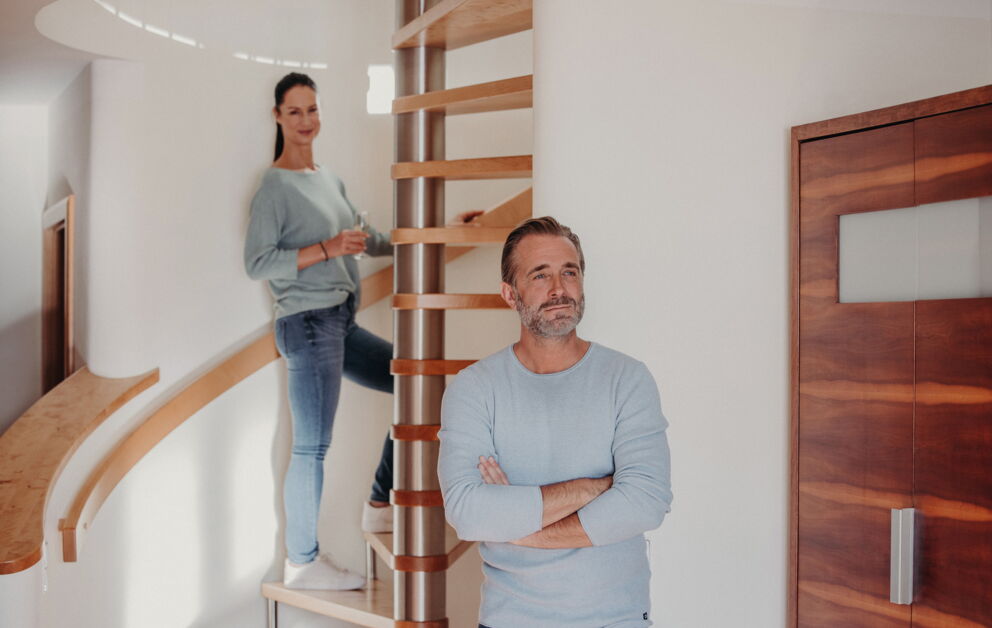 Zwei Menschen entspannen im modernen Wohnraum mit Holztreppe und Holztür.