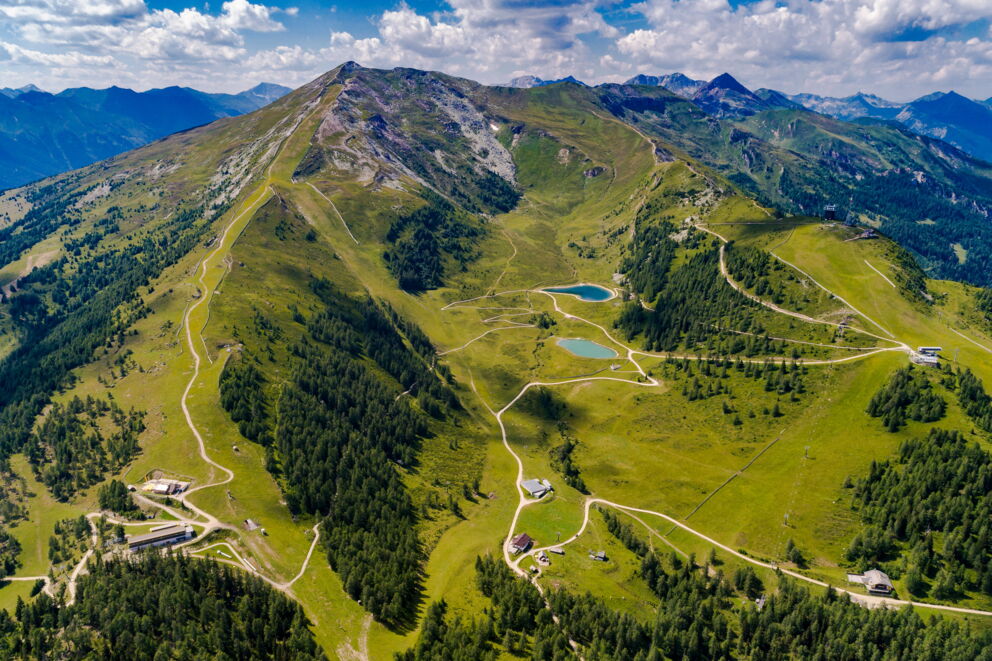 Vast green mountains with clear lakes under a blue sky and white clouds