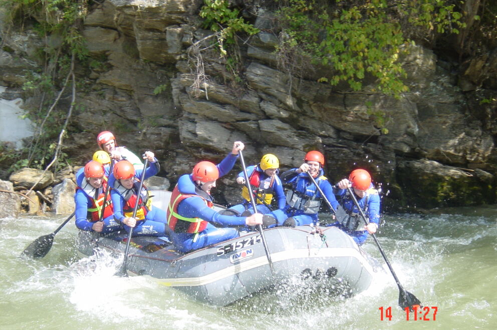 Gruppe Menschen beim Rafting in einem Schlauchboot auf einem spritzigen Fluss.