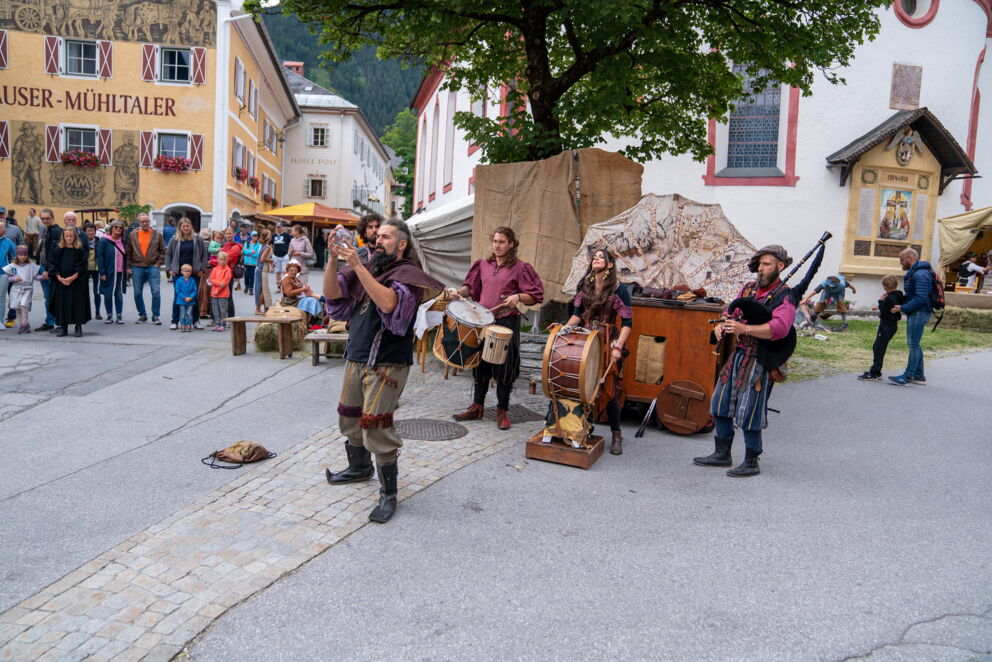 Straßenmusiker in mittelalterlicher Kleidung spielen vor Publikum auf einem historischen Fest.
