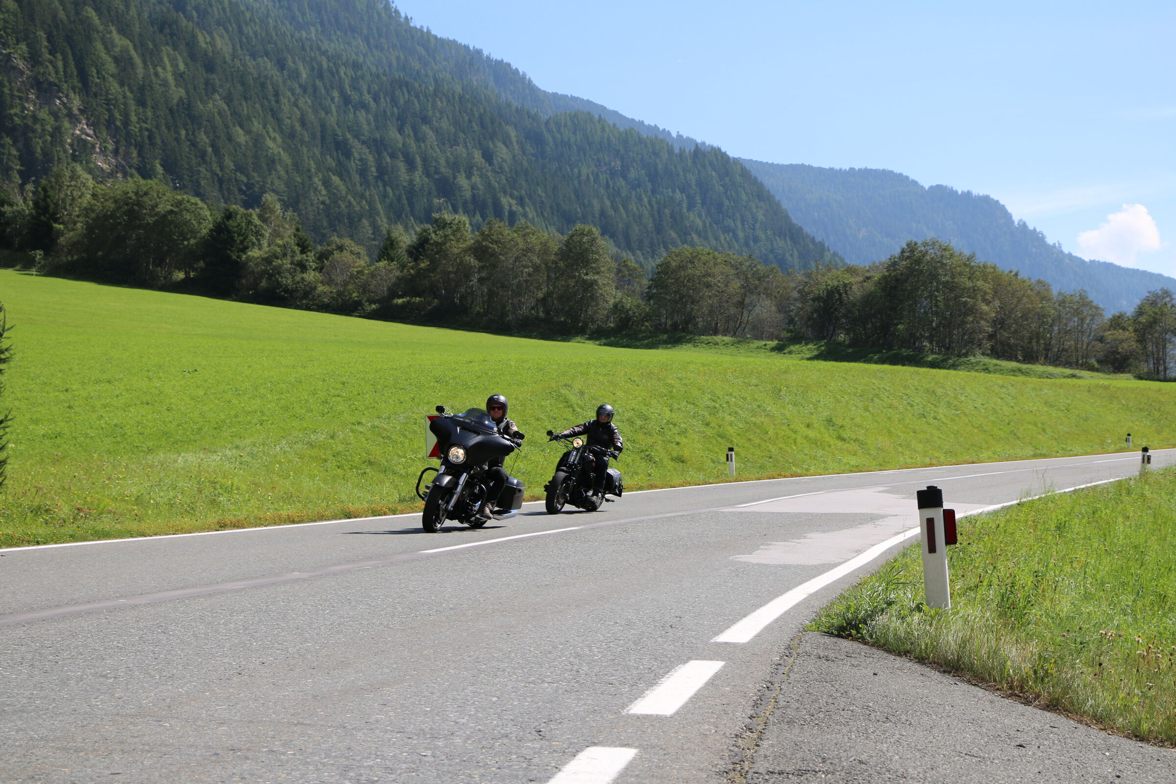 Zwei Motorräder auf kurvenreicher Straße vor malerischer Bergkulisse.