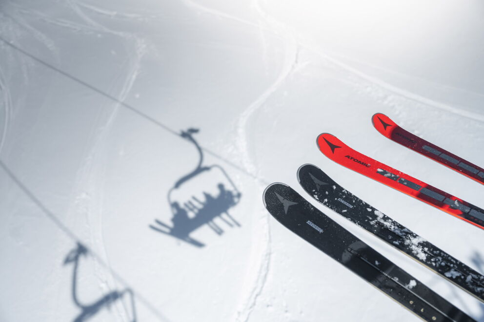 Skier im Schnee unter einem Sessellift auf einer Skipiste.