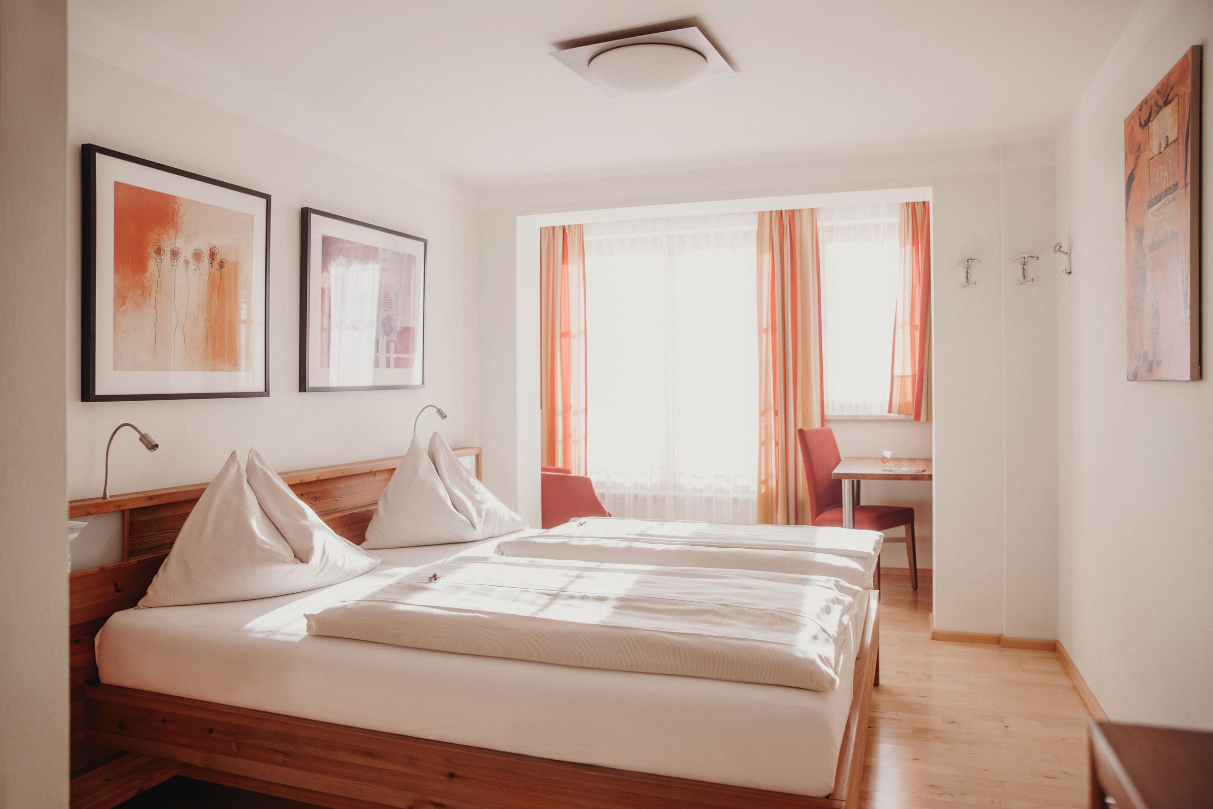 Helles Zimmer mit großem Bett, Holzdetails und roten Vorhängen für gemütliche Atmosphäre.