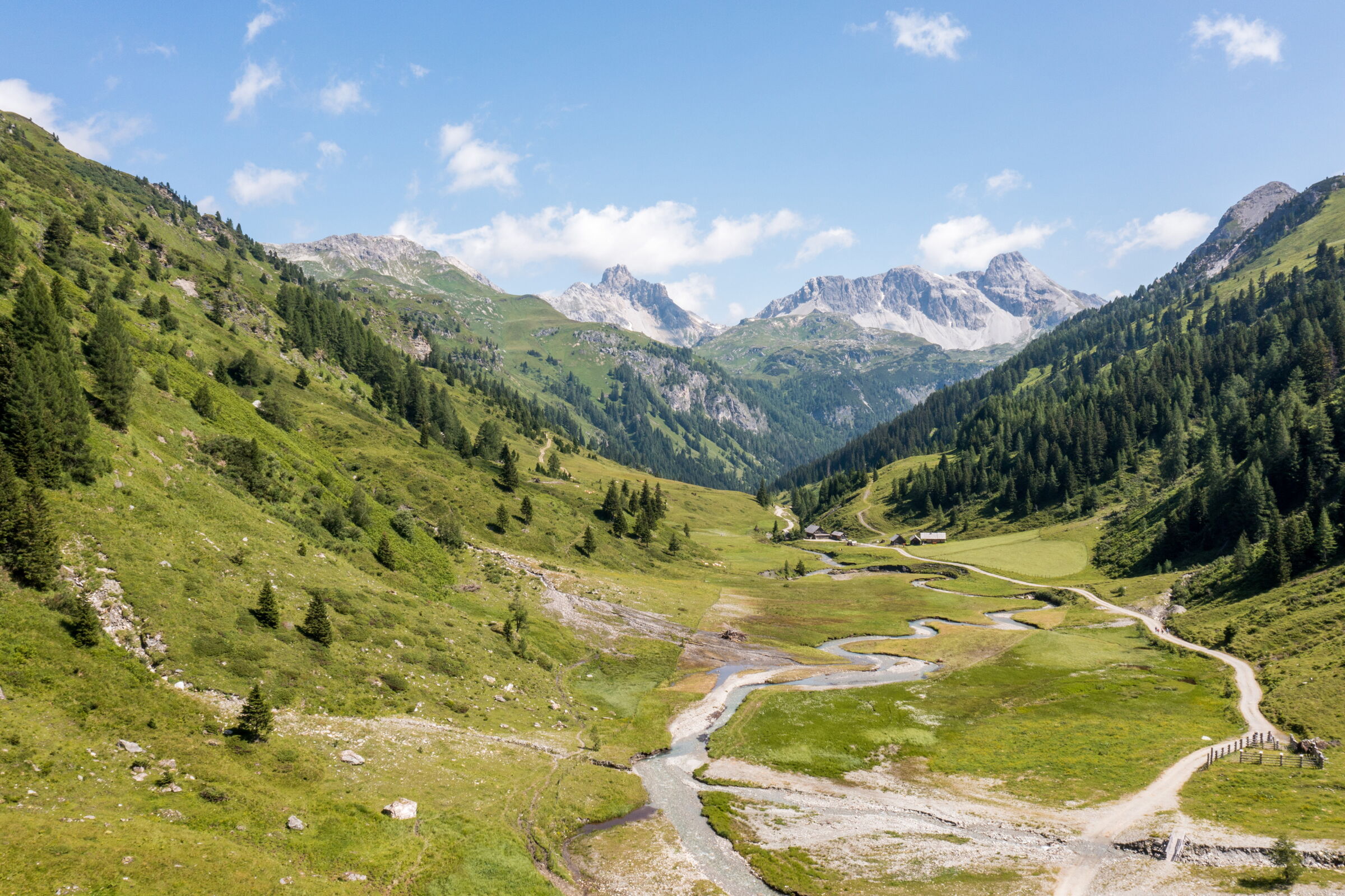 Grüne Täler und majestätische Berge unter strahlend blauem Himmel.