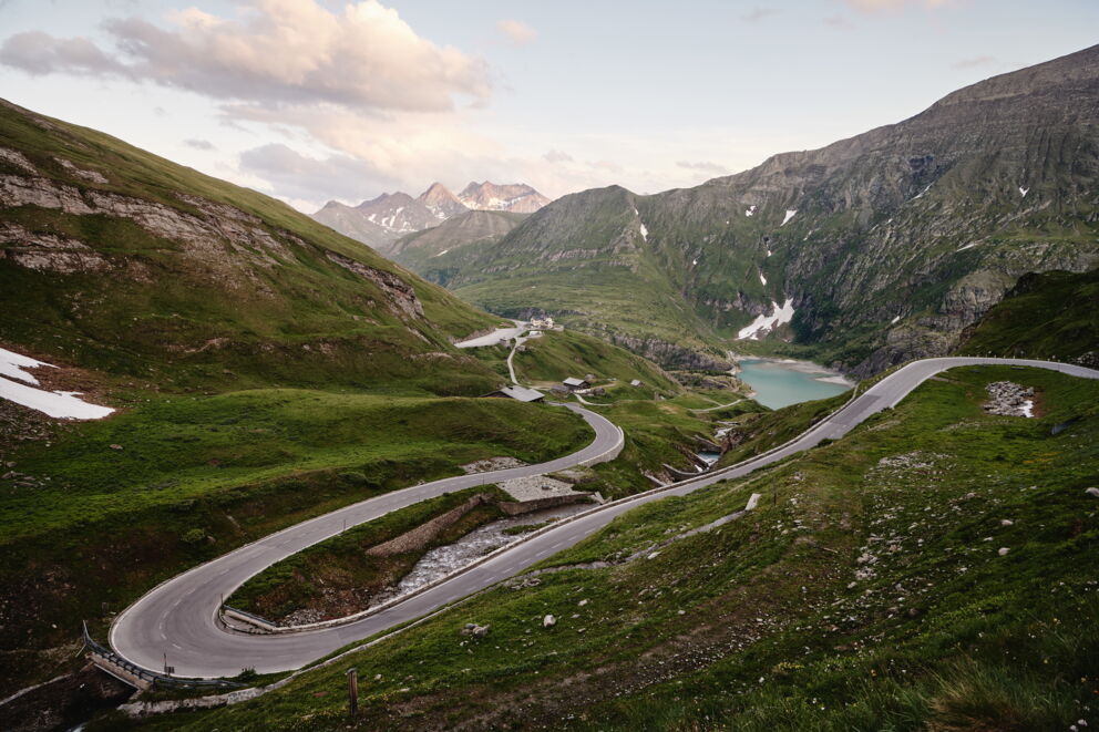 Eine kurvige Bergstraße im Großglockner-Gebiet mit Blick auf majestätische Gipfel und eine atemberaubende Landschaft im Hintergrund, sehr beliebt bei Motorradfahrern, ein Fahrerlebnis und Naturerlebnis