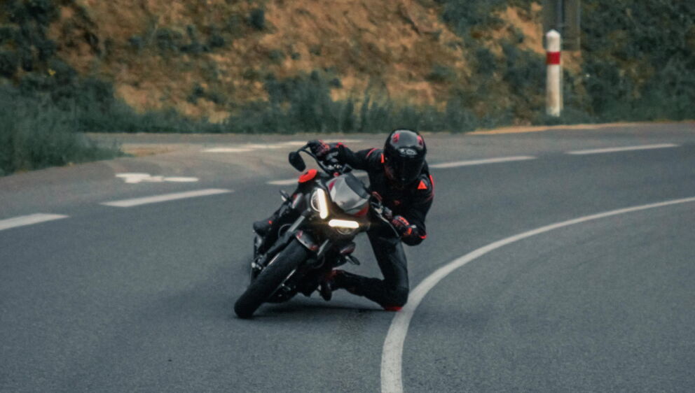Ein Motorradfahrer, der eine sehr enge Kurve nimmt und dabei mit seinen Knieprotektoren am Boden schleift.