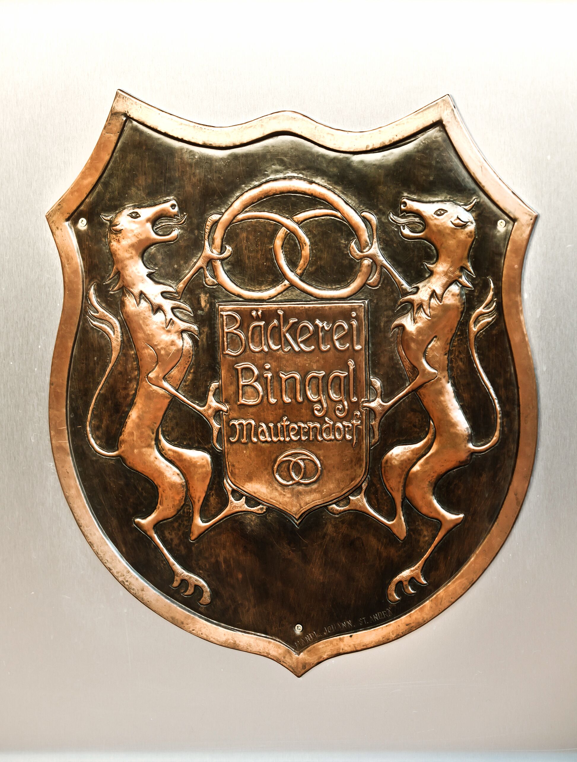Historisches Emblem der Bäckerei Binggl in Mauterndorf, kunstvoll in Metall gestaltet.