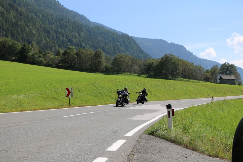 Zwei Motorradfahrer auf einer Bergstraße in Österreich in einer leichten Rechtskurve.