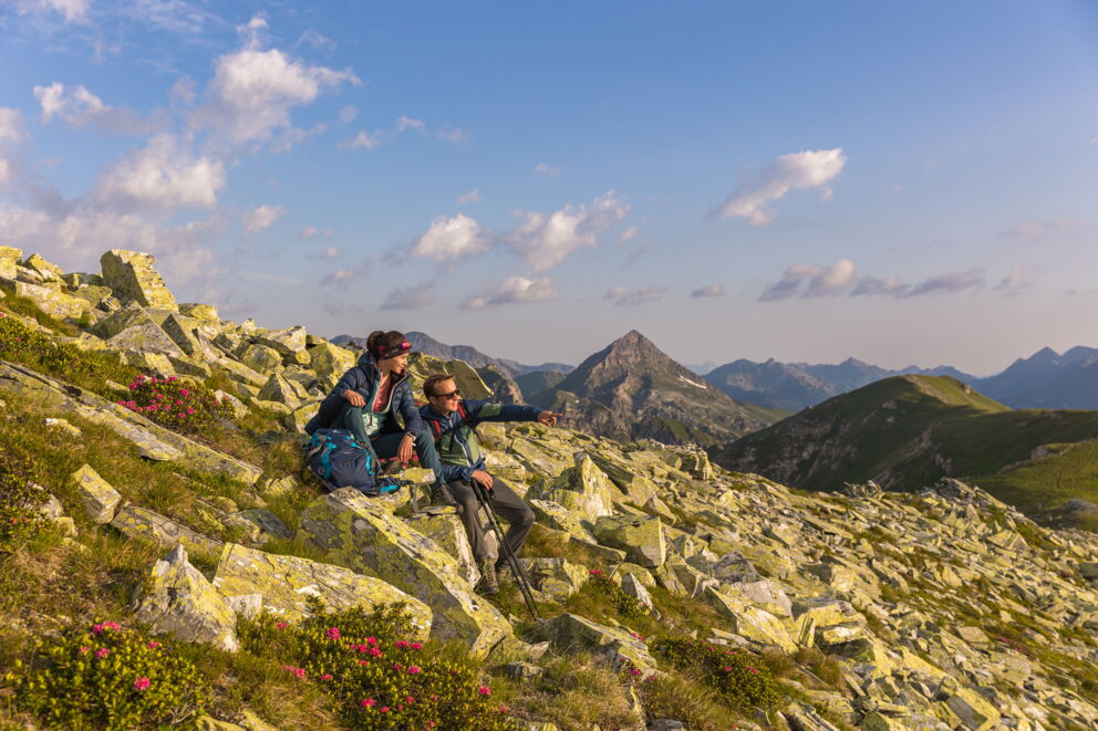 Zwei Wanderer genießen den Panoramablick in den Bergen bei Sonnenschein.