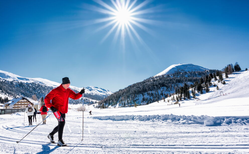 Ein Langläufer fährt im Winterurlaub mit seinen Langlaufskiern auf einer perfekt präparierten Loipe im Salzburger Lungau