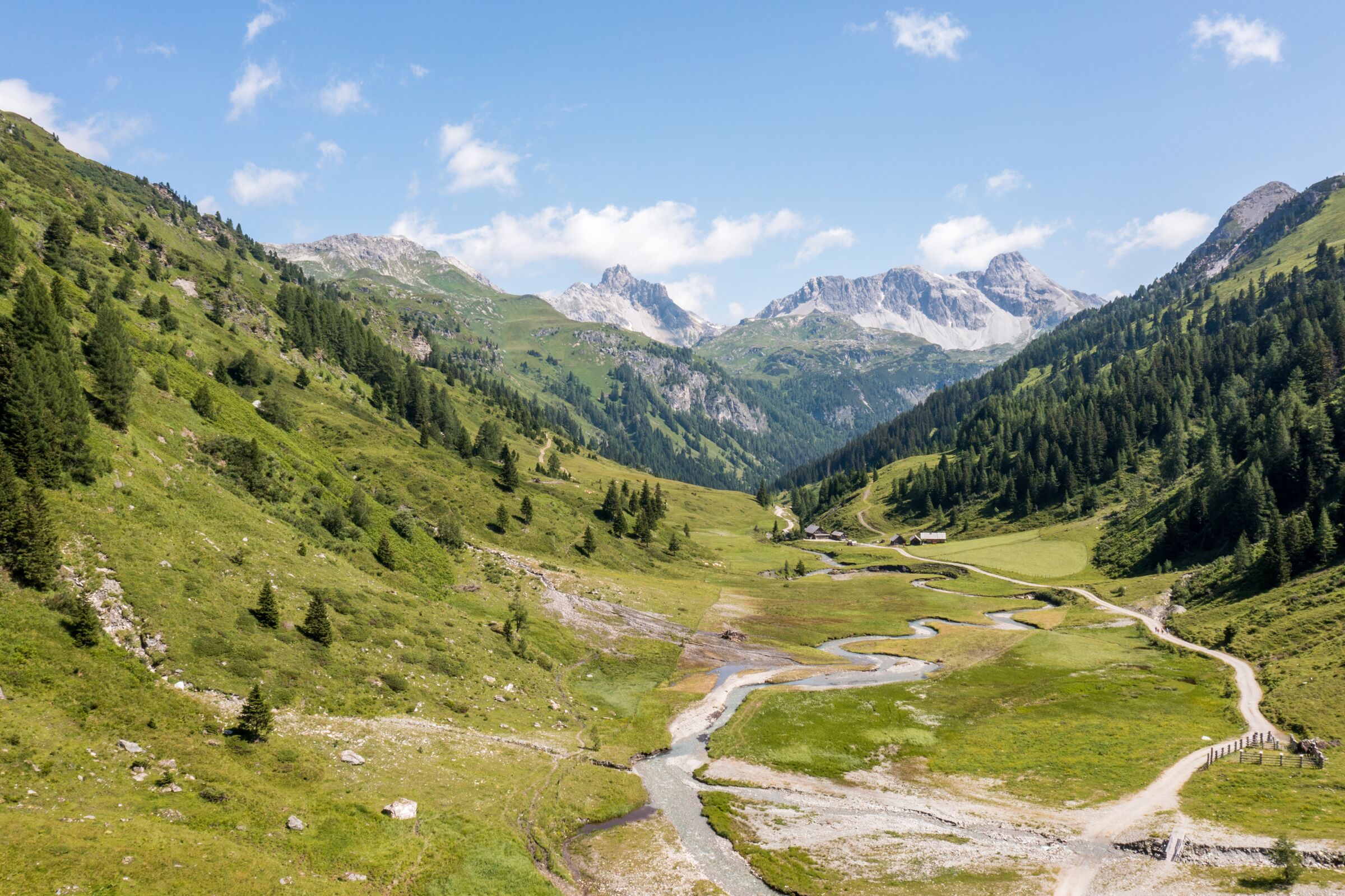 Grüne Täler und majestätische Berge unter strahlend blauem Himmel.
