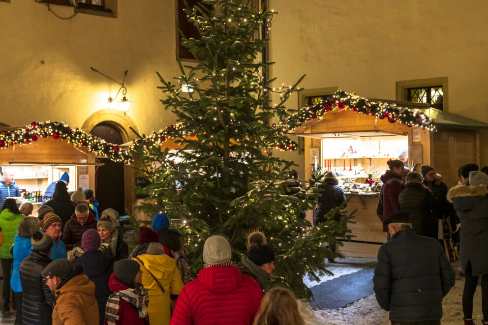 Menschen genießen den Weihnachtsmarkt mit leuchtenden Lichtern und dekorierten Ständen.
